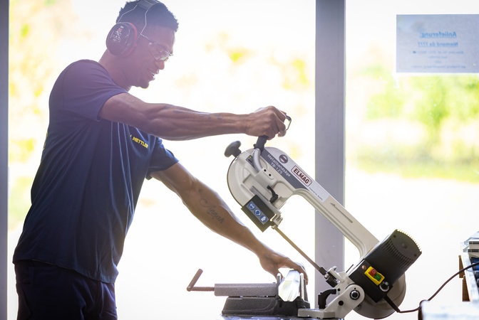 Ein Mettler-Mitarbeiter mit Schutzausrüstung bei der Arbeit an einer Metallbandsäge