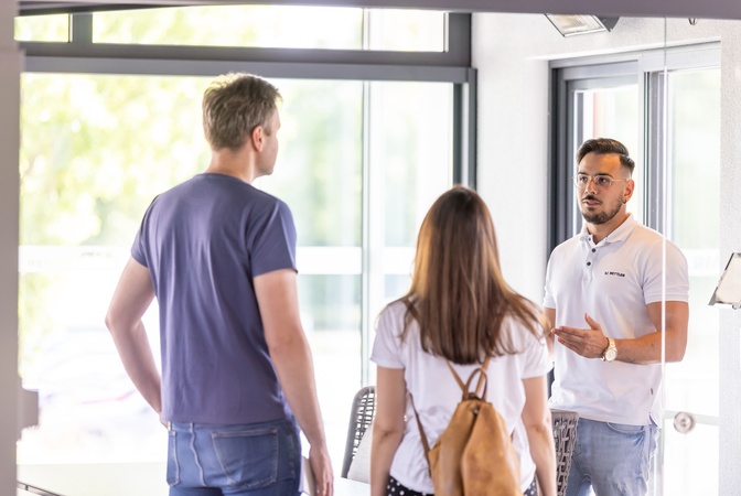 Ein Berater im Gespräch mit einem Paar in einem hellen, modernen Raum
