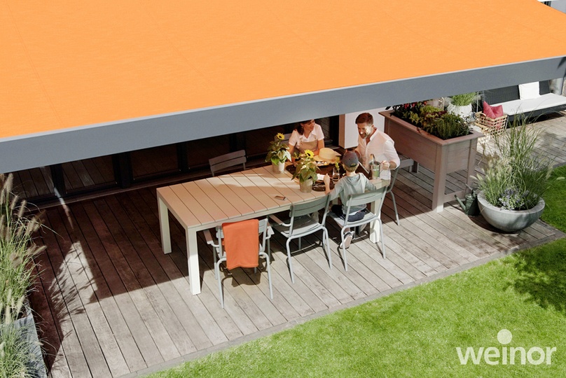 Familie sitzt im Schatten einer Kassettenmarkise auf der Terrasse