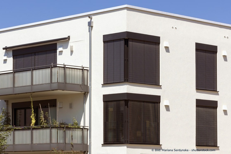 Moderne externe Rollläden an einem Mehrfamilienhaus schützen am Tag vor Sonneneinstrahlung