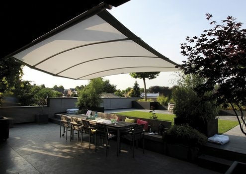 Sonnige Terrasse mit weißer Markise, Esstisch und Pflanzen.