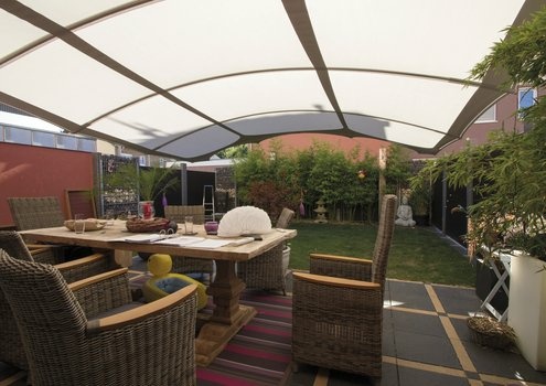Moderne Terrasse mit weißem Vordach, Holztisch, Korbstühlen und grünem Garten.
