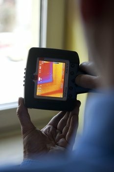 Person hält Wärmebildkamera, die farbige Temperaturunterschiede zeigt.