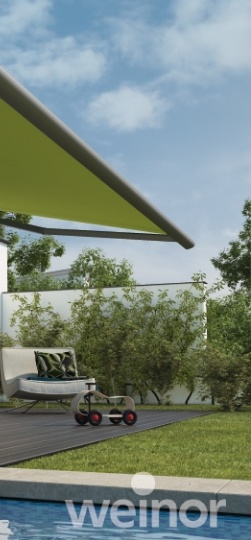 Grüne Markise über Terrasse mit Mähroboter und Pool im Garten unter blauem Himmel.