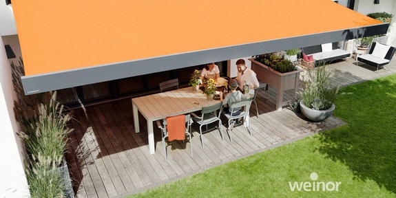 Familie sitzt im Schatten einer Kassettenmarkise auf der Terrasse