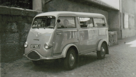 Schwarz-Weiß-Foto eines historischen hellen Lieferwagens mit runder Front, auf der Straße geparkt.