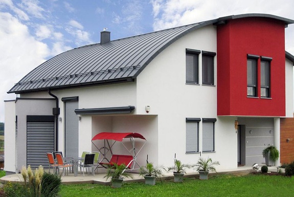 Modernes weißes Wohnhaus mit roter Fassadenpartie und geschwungenem, dunklem Dach.