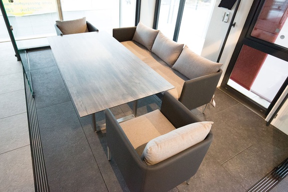 Moderne Sitzecke mit langem, hellem Tisch und zwei grauen Sofas.