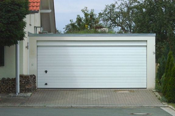 Weißes, modernes Garagentor mit Flachdach und Ziegelpflasterung.