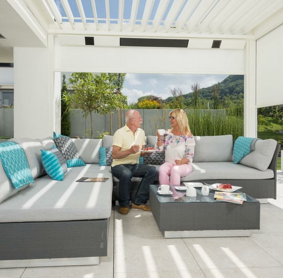 Schwangere Frau und Mann trinken Kaffee auf moderner Terrasse mit Pergola.