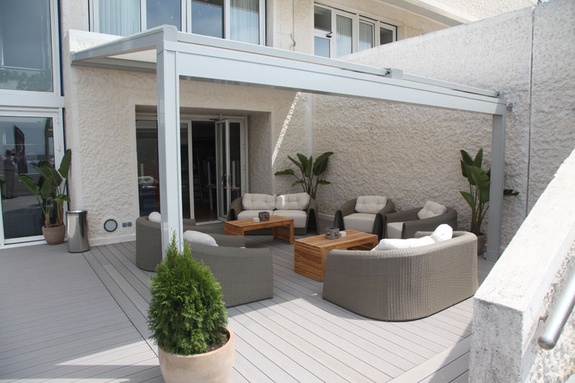 Gemütliche, moderne Außenterrasse mit grauer Pergola, Lounge-Möbeln und Pflanzen.