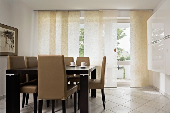 Moderne Essecke mit dunklem Holztisch, beigen Stühlen und gemusterten Schiebegardinen.