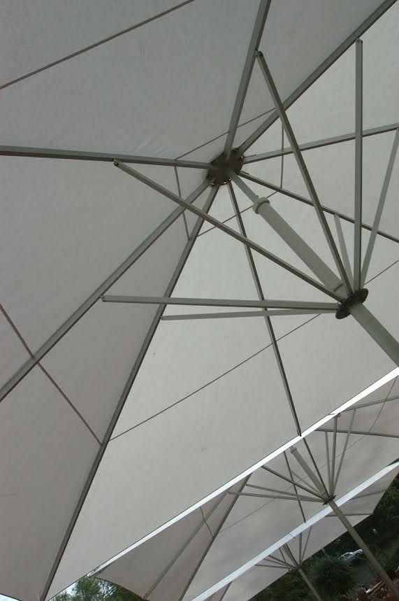 Unterseite von hellen Sonnenschirmen mit Metallgestell, Blick nach oben.