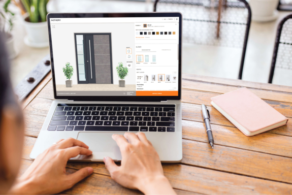 Person konfiguriert Haustür am Laptop auf einem Holztisch.