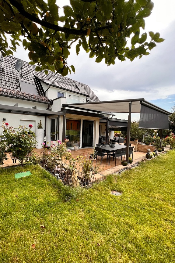 Das linke Glas-Terrassendach ist dezent integriert und lädt zum Grillen bei jedem Wetter ein