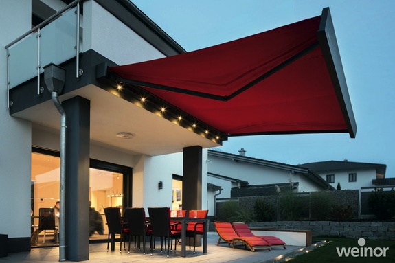 Ausgefahrene rote Markise an der Terrasse mit roten Sitzmöbeln