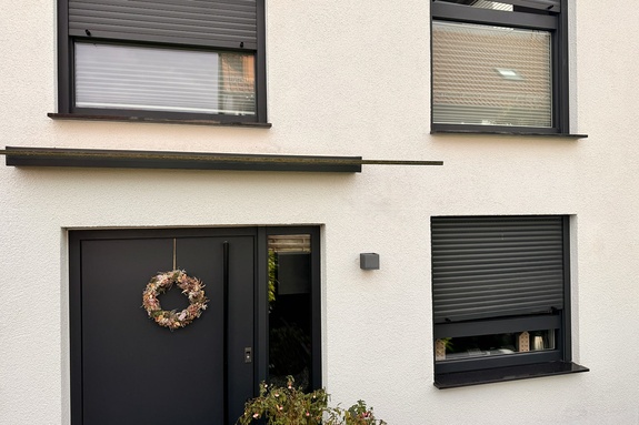Haus mit mehreren schief hängenden Rollläden