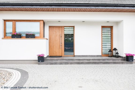 Hauseingang mit hochwertiger Haustür aus Holz und Glasfenster daneben