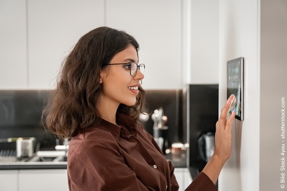 Frau bedient Tablet mit Smart Home Steuerung in der Küche